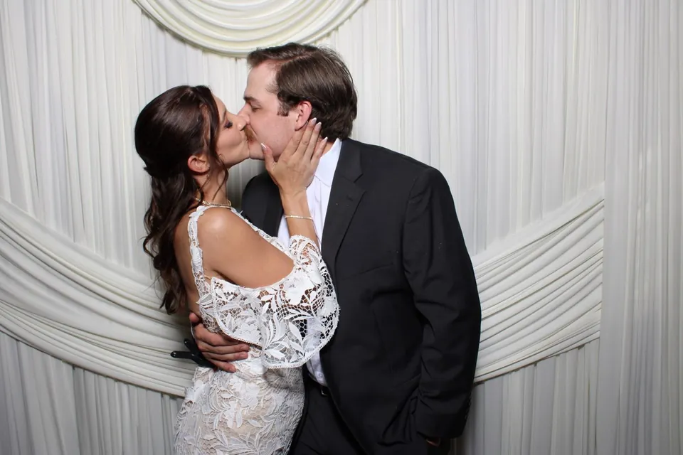Bride and groom kissing in front of ivory drapery