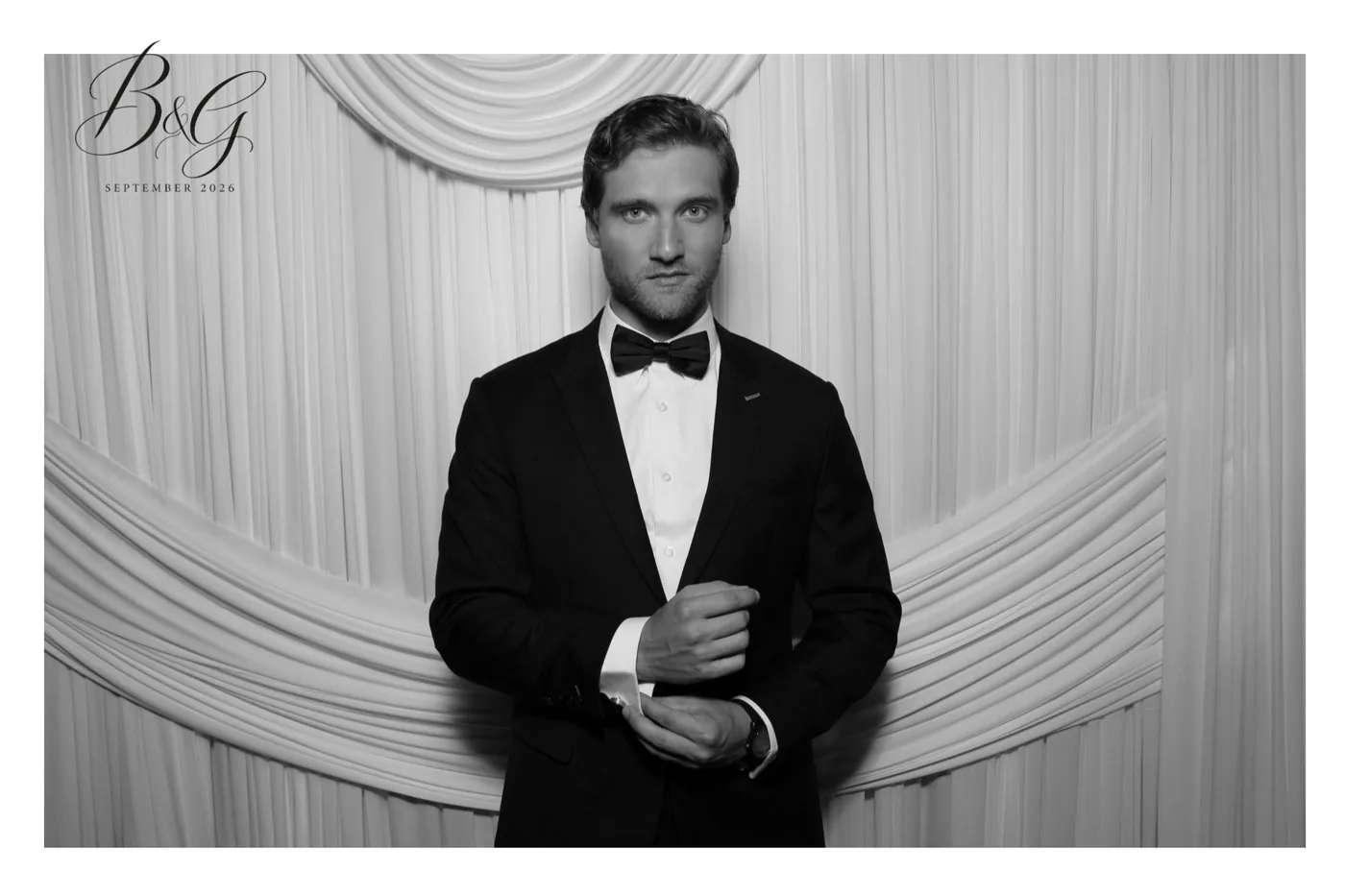 Black and white glam portrait of the groom adjusting his cufflinks