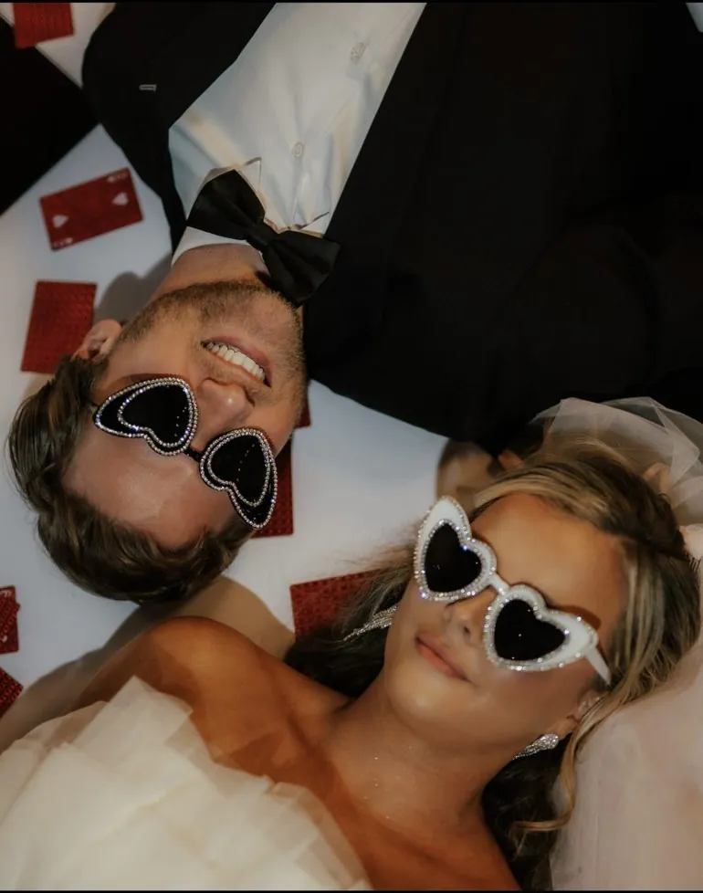 Newlyweds lying on white tulle in heart sunglasses